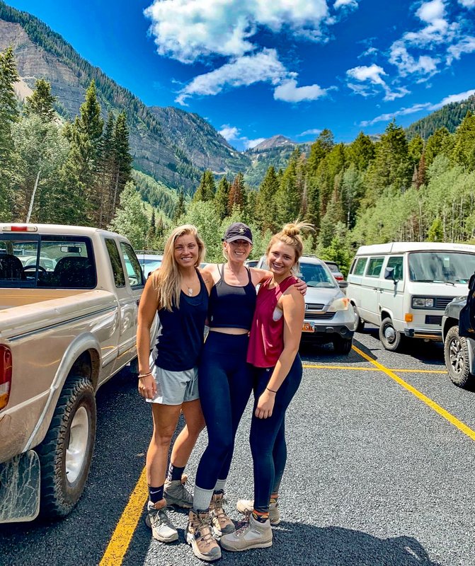 Three participants smiling at mountain trailhead
