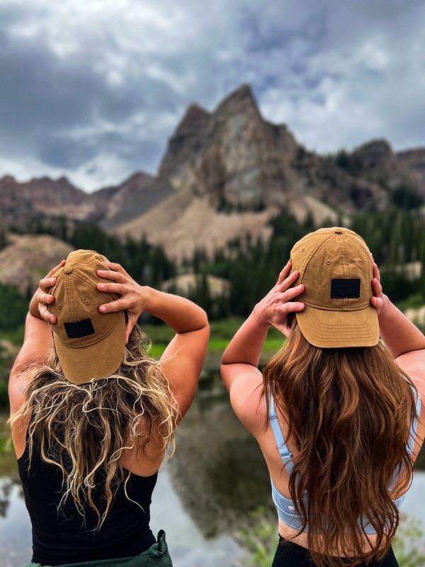 Two participants with caps overlooking mountain landscape